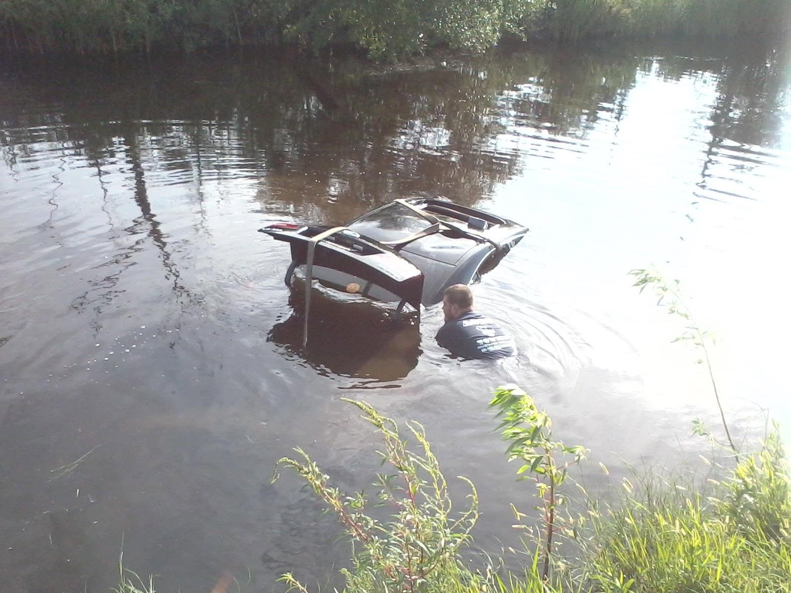 Before: a car submerged in the bayou with a recovery strap attached
