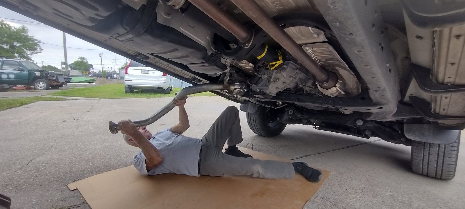 Mechanic replacing an exhaust pipe under a vehicle