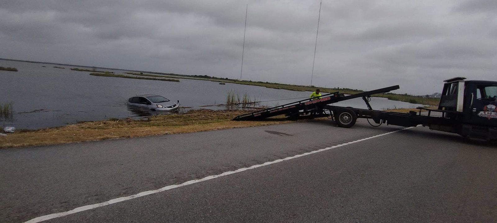 Tow truck winching a car out of the bayou