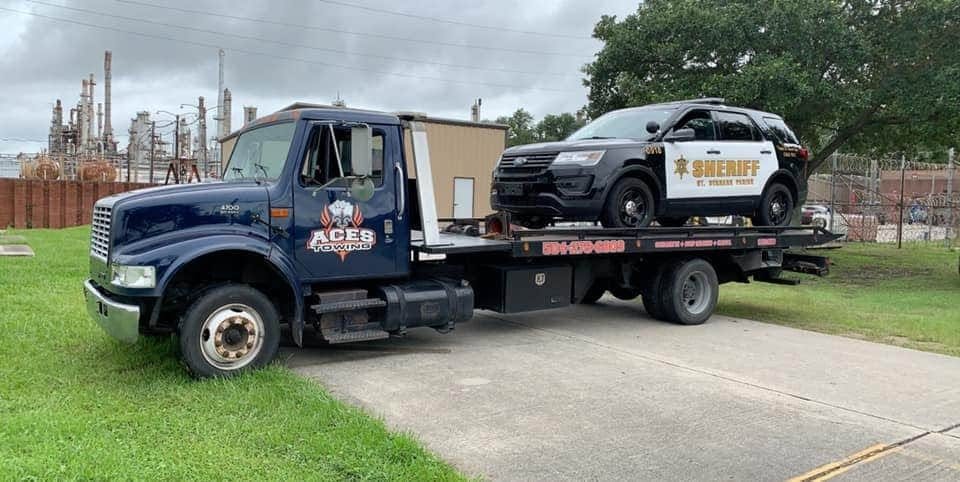 Aces Towing flatbed carrying a sheriff's SUV